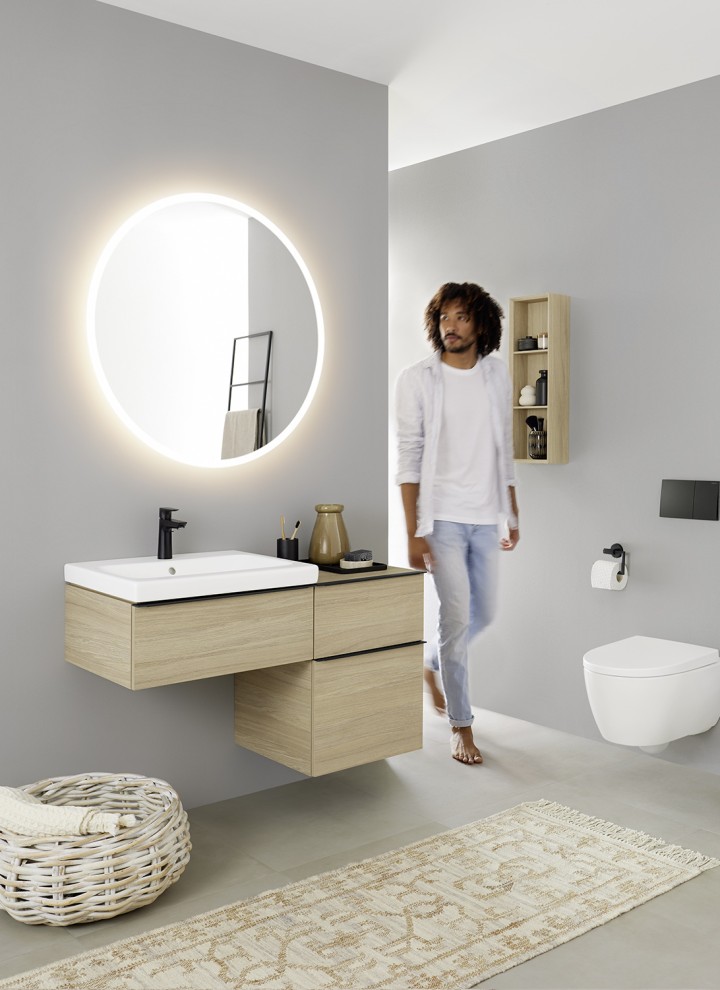 Homme dans une salle de bains avec miroir rond Geberit Option