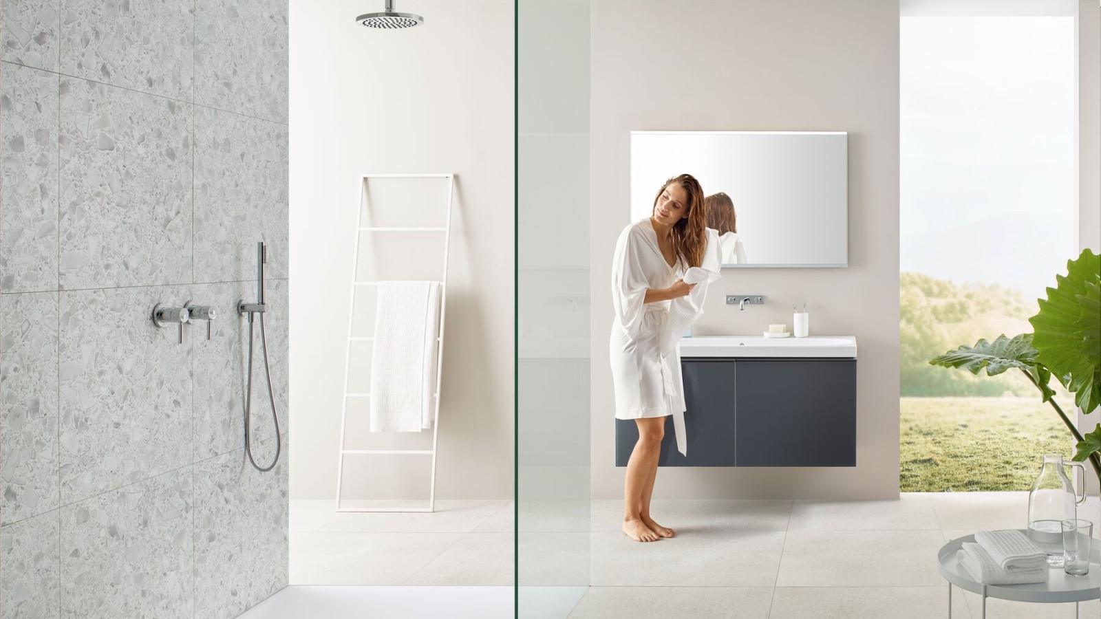 Femme séchant ses cheveux avec une serviette dans une salle de bain avec douche ouverte et grands carreaux de style terrazzo. Femme séchant ses cheveux avec une serviette dans une salle de bain avec douche ouverte et grands carreaux de style terrazzo.