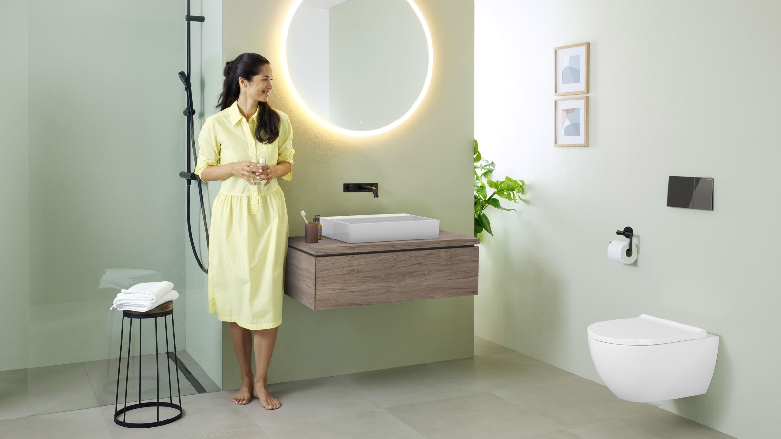 Femme dans une salle de bains comprenant un miroir Geberit Option et un lavabo Geberit VariForm Femme dans une salle de bains comprenant un miroir Geberit Option et un lavabo Geberit VariForm