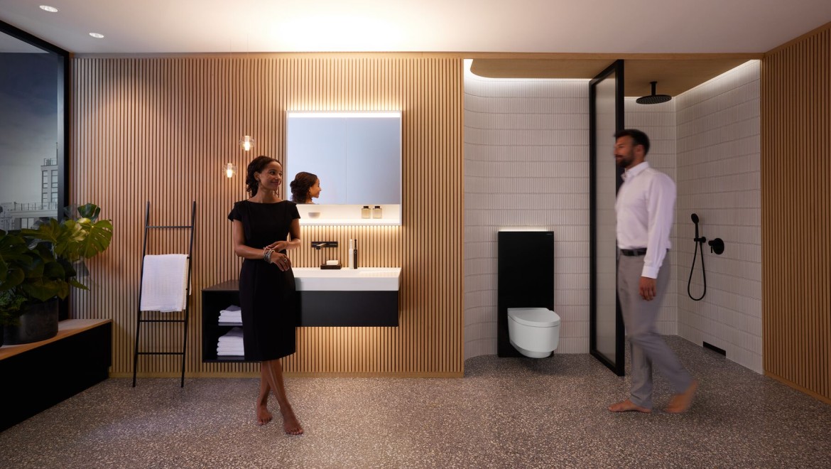 Homme et femme dans une salle de bains parfaitement éclairée avec les produits Geberit ONE