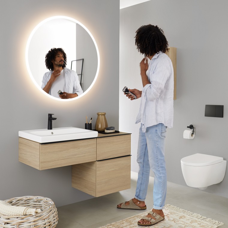 Homme se regardant dans un miroir rond lumineux Geberit Option Homme se regardant dans un miroir rond lumineux Geberit Option