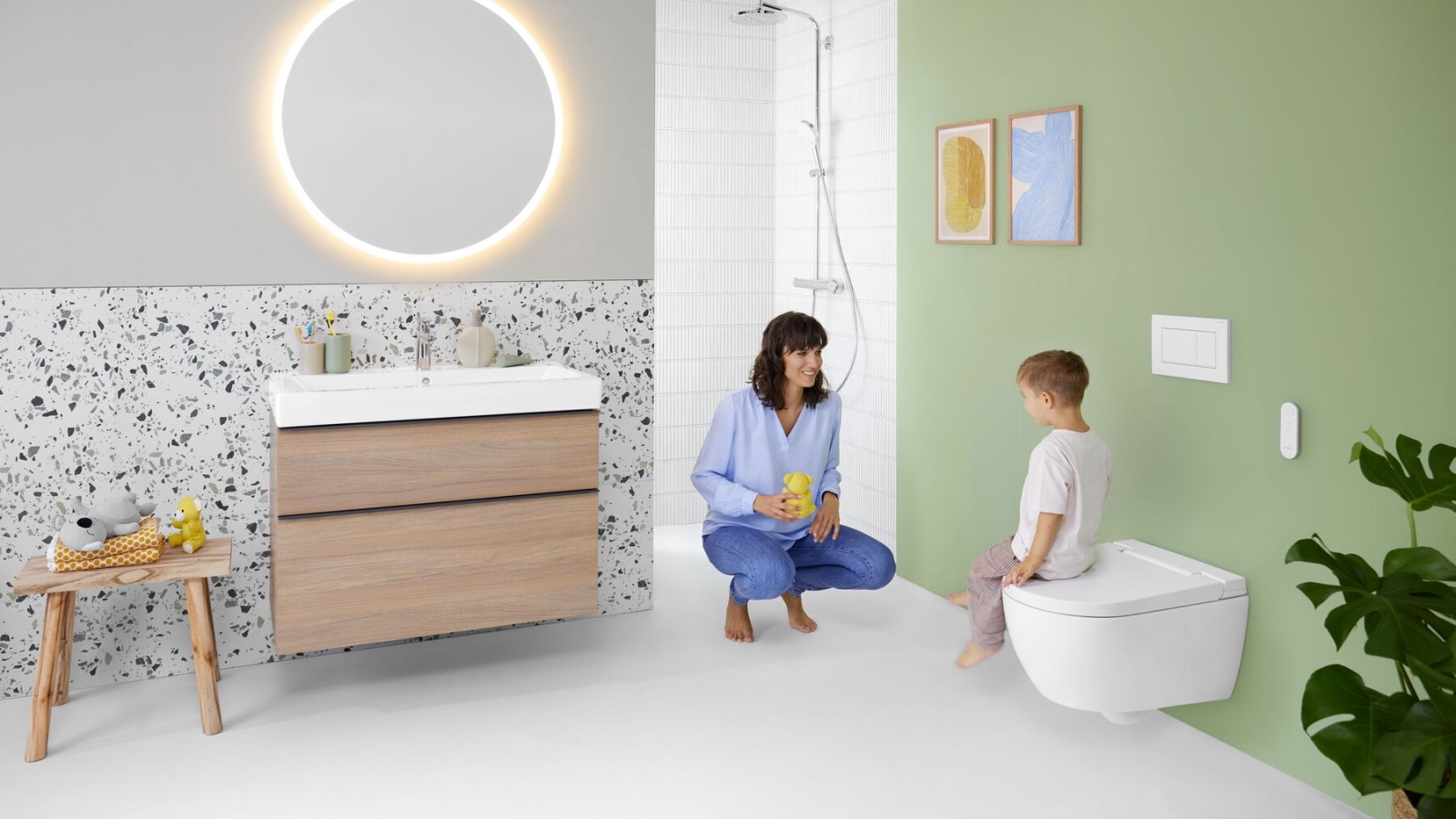 Une femme et un enfant dans une salle de bains avec un WC lavant Geberit AquaClean Alba