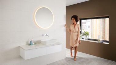 Une femme dans une salle de bains moderne avec une palette de couleurs brunes - la dernière tendance dans la salle de bains - et une combinaison de lavabos Mix & Match.