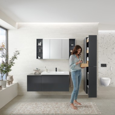 Femme ouvrant une colonne haute avec beaucoup d’espace de rangement pour une salle de bains moderne, Geberit Acanto Femme ouvrant une colonne haute avec beaucoup d’espace de rangement pour une salle de bains moderne, Geberit Acanto