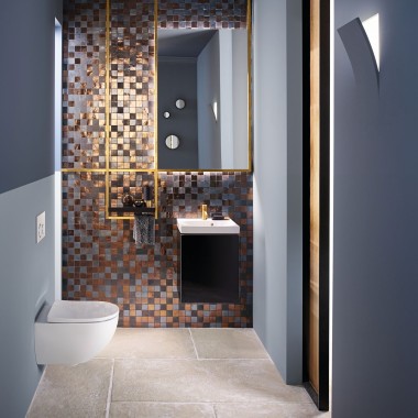 Vue d'une salle de bains moderne pour invités avec un WC Acanto et d'un lavabo Acanto devant un panneau arrière en mosaïque.