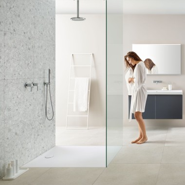Femme dans une salle de bains avec douche à l’italienne et receveur de douche Geberit Olona Femme dans une salle de bains avec douche à l’italienne et receveur de douche Geberit Olona