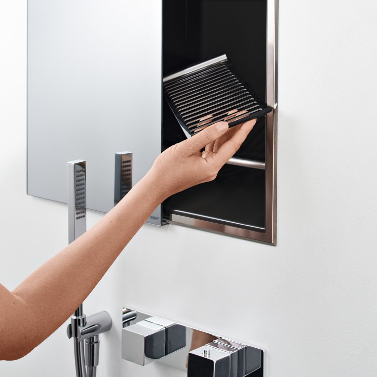 Main de femme positionnant une étagère dans la niche de rangement de la douche (© Geberit) Main de femme positionnant une étagère dans la niche de rangement de la douche (© Geberit)