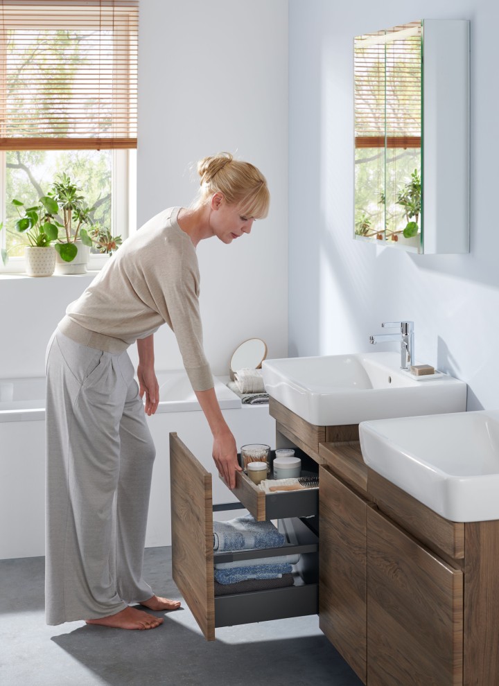 Femme dans une salle de bains blanche de la ligne Geberit Renova Plan