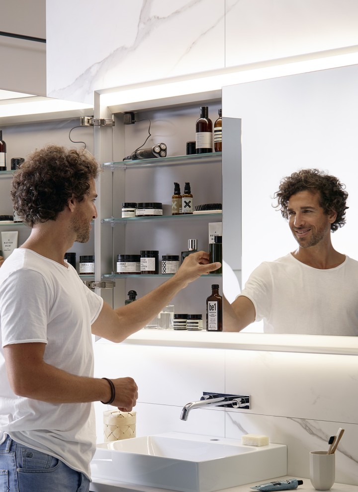 Homme dans une salle de bains avec armoire de toilette Geberit ONE Homme dans une salle de bains avec armoire de toilette Geberit ONE