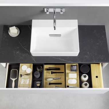 Vue de dessus dans un tiroir de lavabo Geberit ONE ouvert avec des boîtes d’organisation Vue de dessus dans un tiroir de lavabo Geberit ONE ouvert avec des boîtes d’organisation