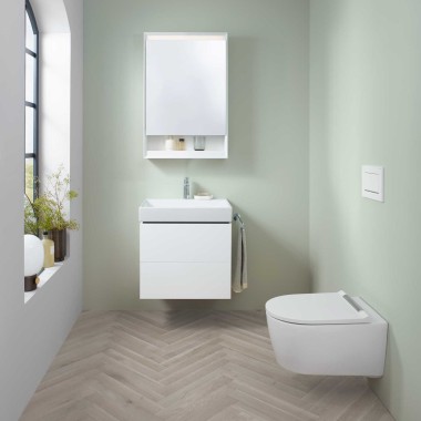 Zone lavabo Geberit ONE avec petit lavabo, meuble sous lavabo et armoire de toilette, ainsi qu'un WC lavant.