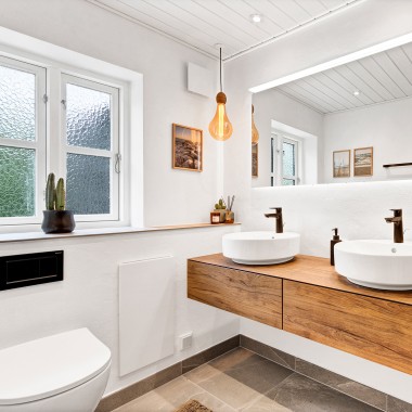 Salle de bains lumineuse et rénovée avec deux lavabos ronds, un grand miroir et des meubles de salle de bains en bois (© @triner2 et @strandparken3)