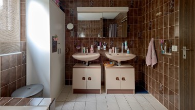 La salle de bains avec carrelage marron et deux lavabos