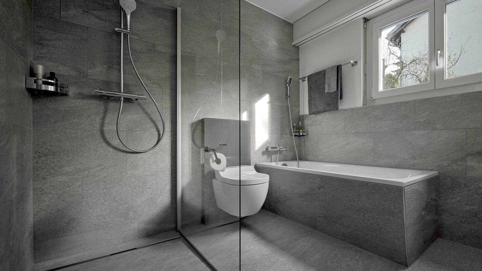 Un WC lavant entre une douche de plain-pied et une baignoire Un WC lavant entre une douche de plain-pied et une baignoire