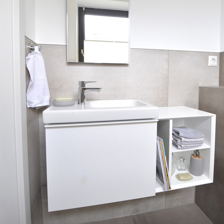 Vue sur la salle de bains dʼinvités avec lavabo et armoires Vue sur la salle de bains dʼinvités avec lavabo et armoires