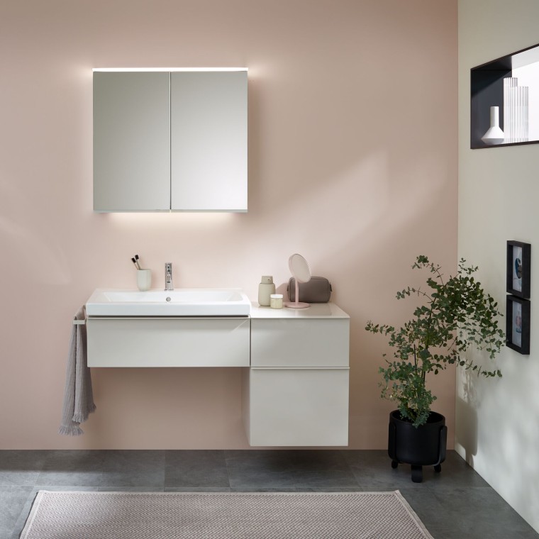 Espace lavabo avec meubles, lavabo et armoire de toilette de Geberit devant un mur pastel Espace lavabo avec meubles, lavabo et armoire de toilette de Geberit devant un mur pastel