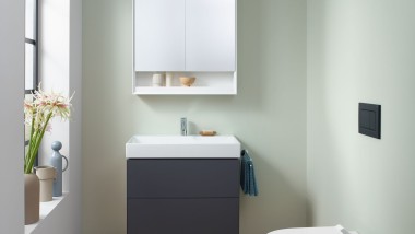 Vue dans un WC dʼinvité avec WC suspendu, armoire de toilette et meuble sous-lavabo de la collection Geberit ONE