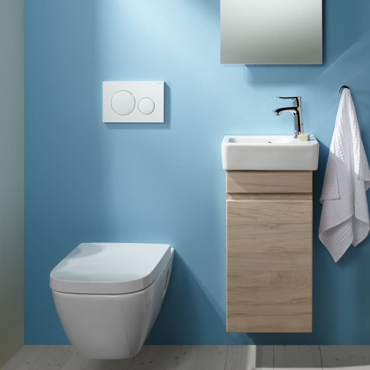 Un WC suspendu Renova Plan et un espace lavabo sur un mur bleu clair Un WC suspendu Renova Plan et un espace lavabo sur un mur bleu clair
