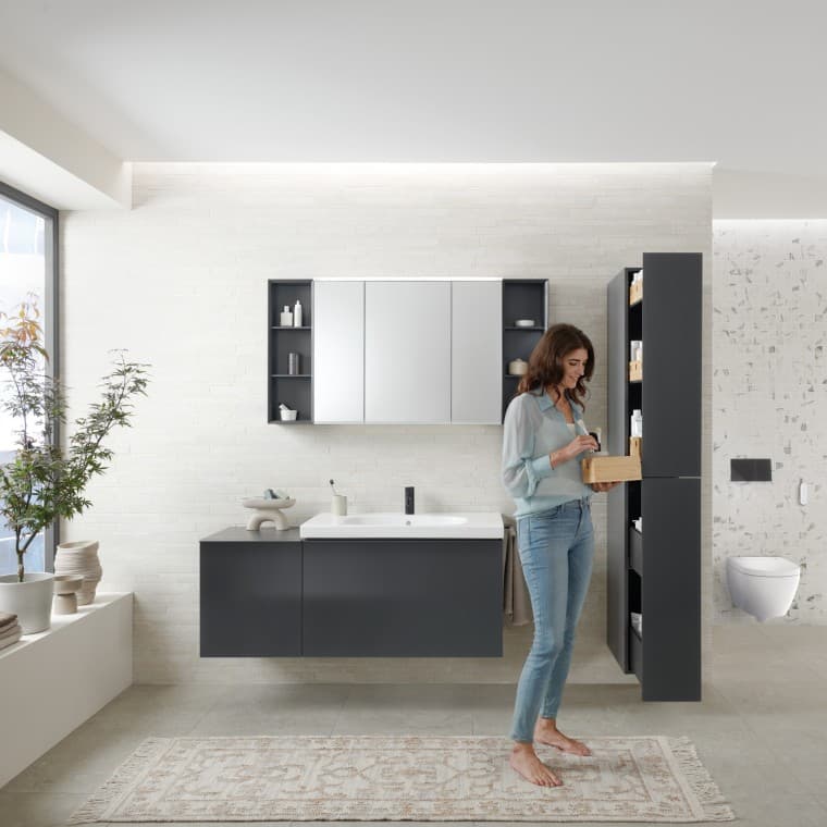 Femme ouvrant une colonne haute avec beaucoup d’espace de rangement pour une salle de bains moderne, Geberit Acanto Femme ouvrant une colonne haute avec beaucoup d’espace de rangement pour une salle de bains moderne, Geberit Acanto