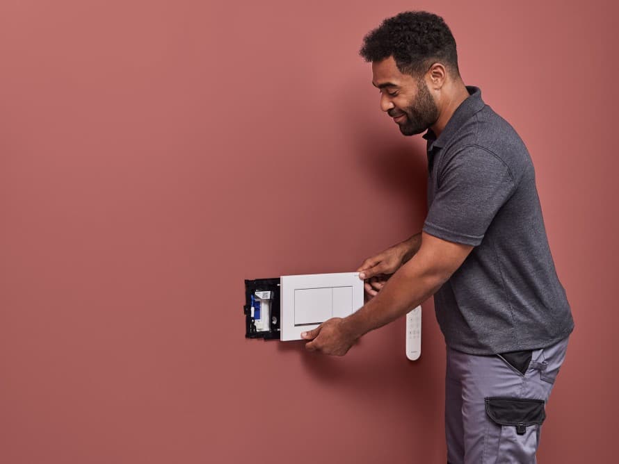 Homme installant l'unité d'extraction des odeurs Geberit DuoFresh Homme installant l'unité d'extraction des odeurs Geberit DuoFresh